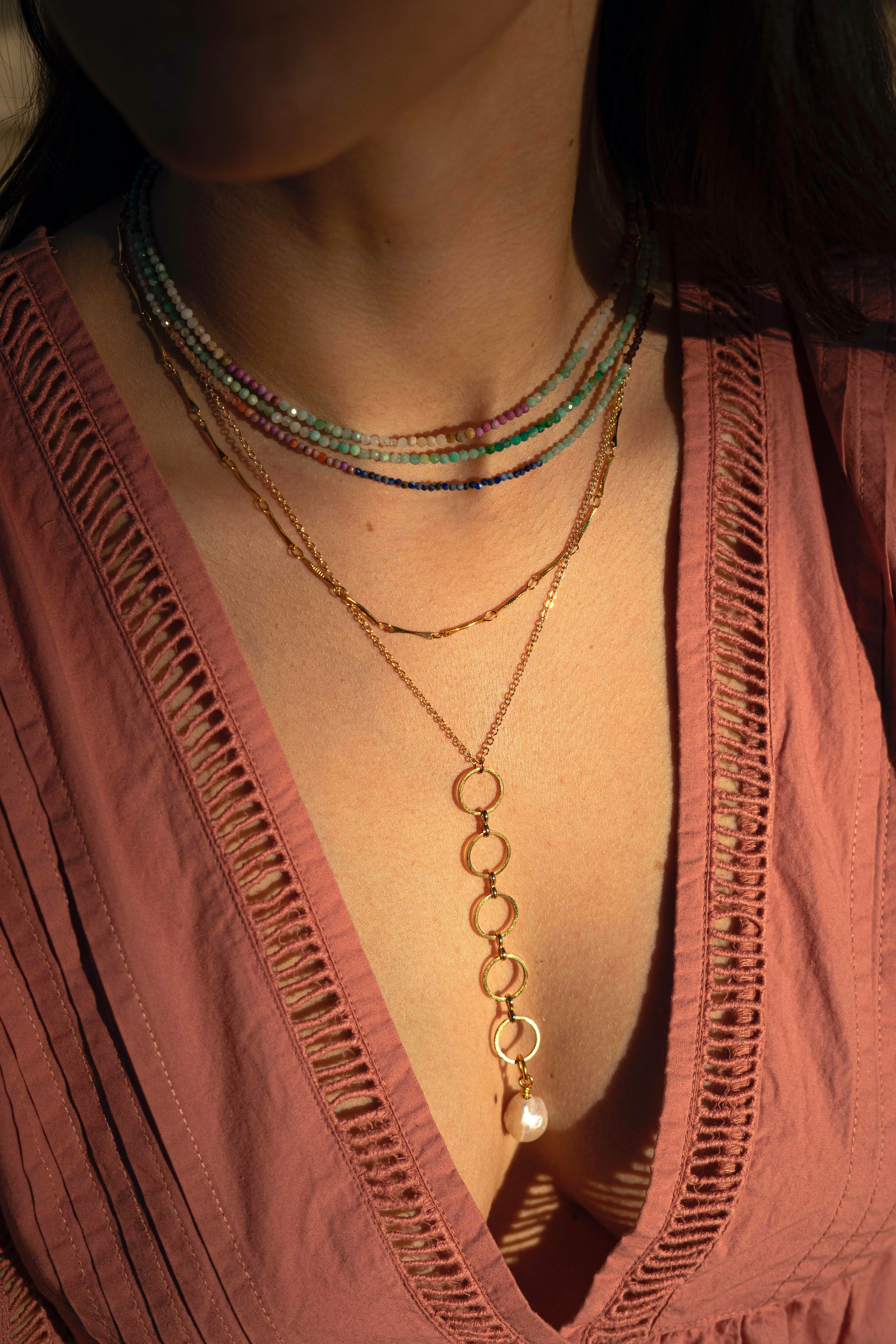 Long gold-plated chain necklace with interlinked circles and a freshwater pearl.