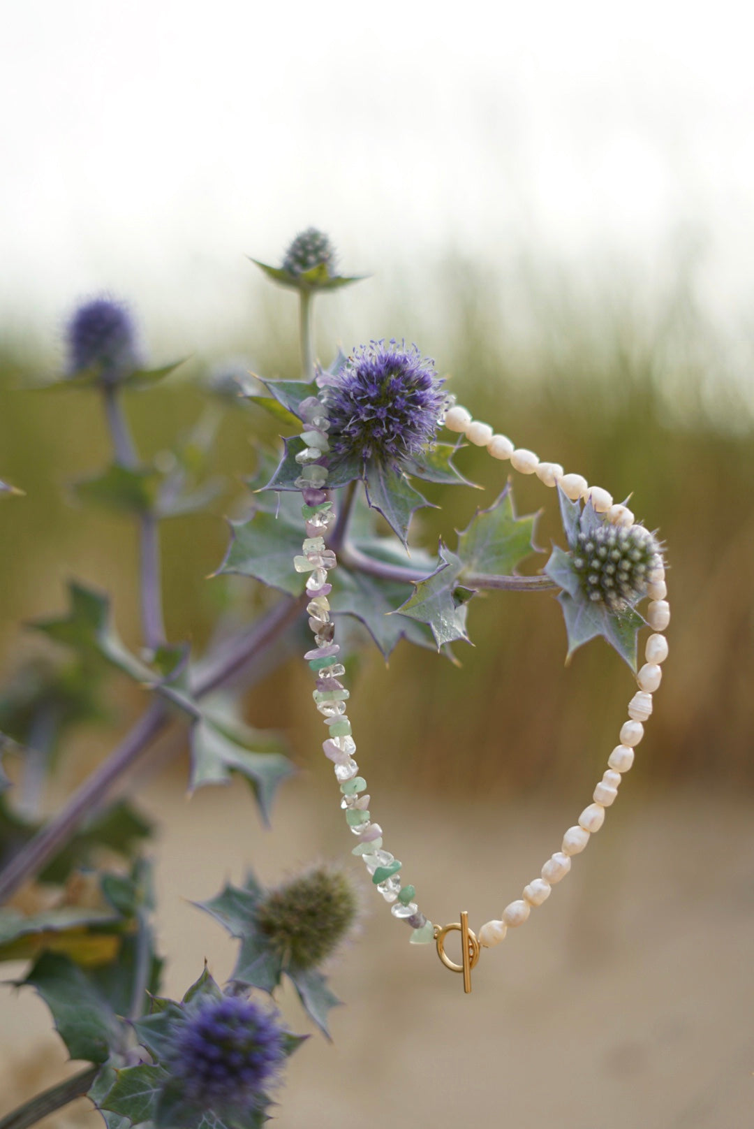 Asymmetric necklace with amethyst, green aventurine, crystal quartz and freshwater pearls with a gold-plated toggle clasp.