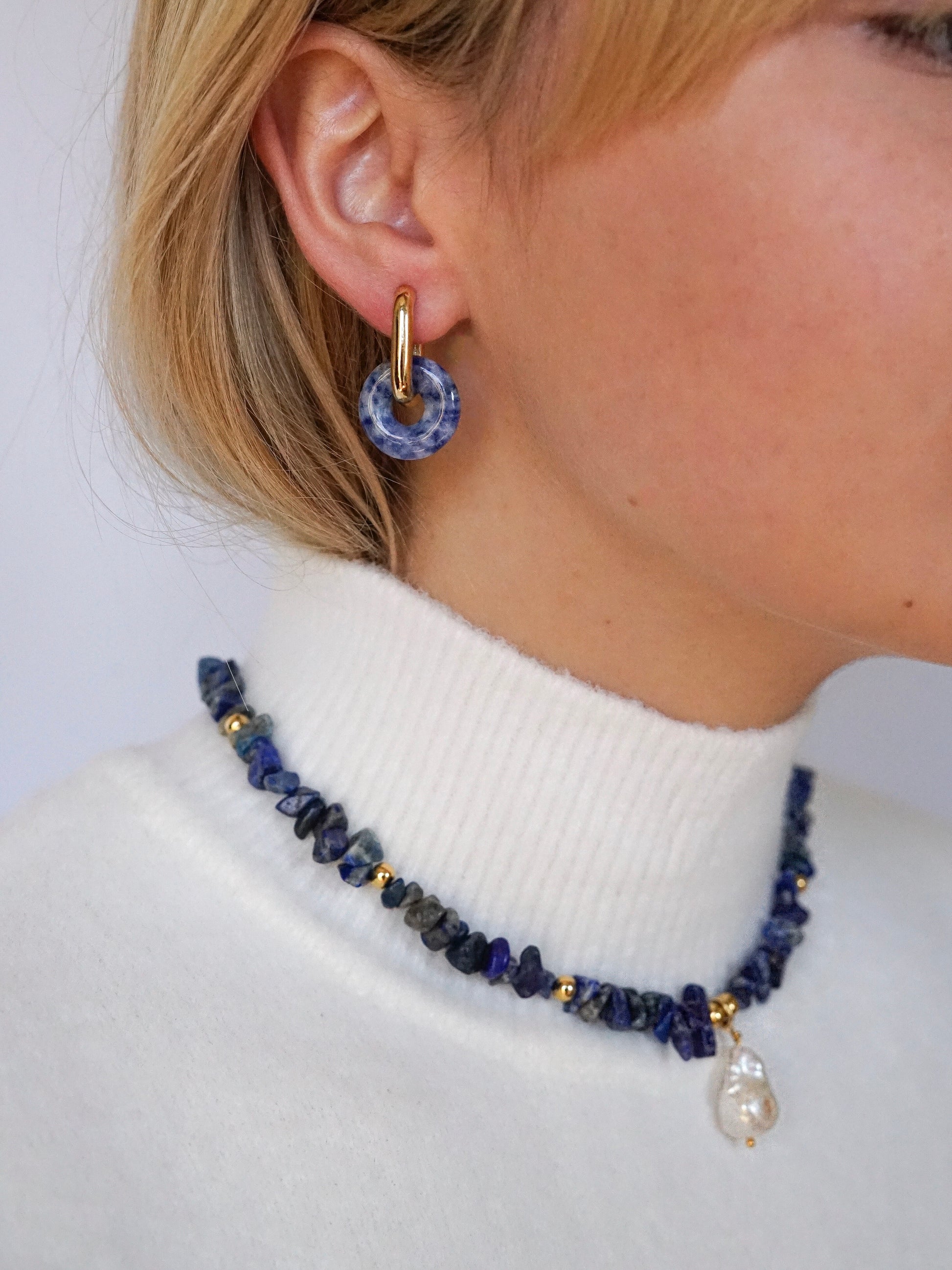 Model in blue spot jasper donut hoop earrings and lapis lazuli and pearl necklace