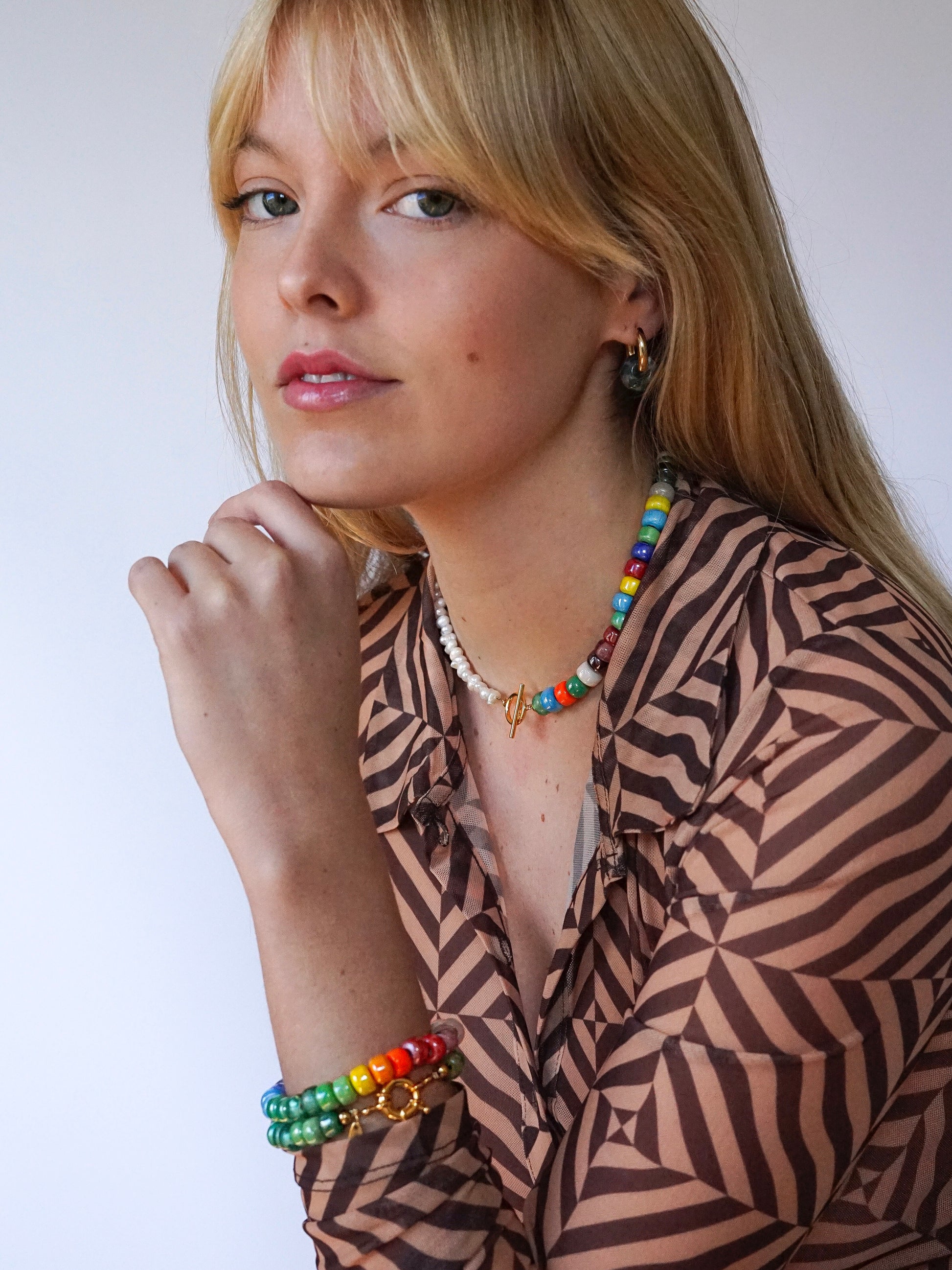 Asymmetric necklace made of recycled rainbow crystal crow beads and freshwater pearls with a gold-plated toggle clasp.