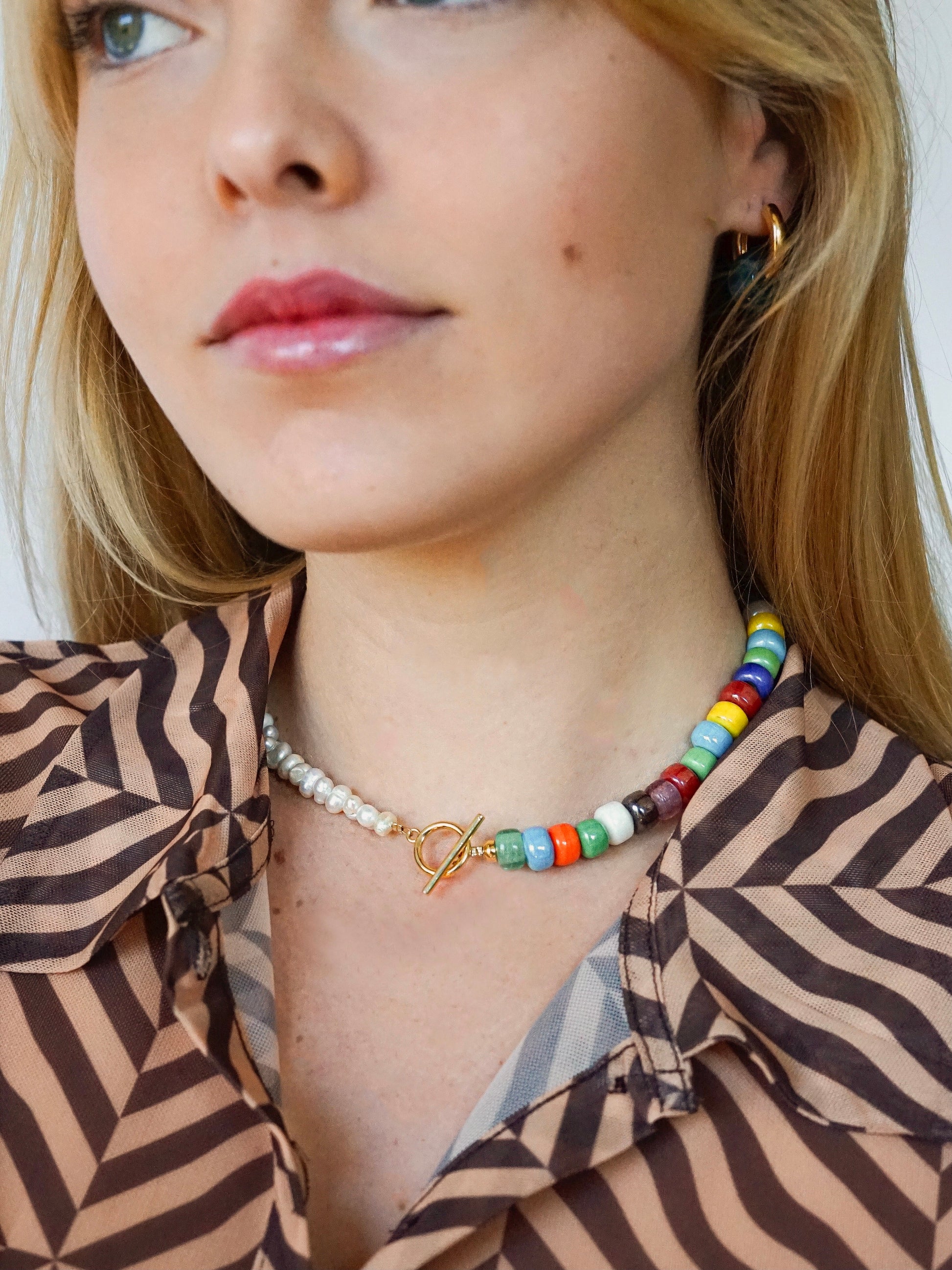 Asymmetric necklace made of recycled rainbow crystal crow beads and freshwater pearls with a gold-plated clasp.