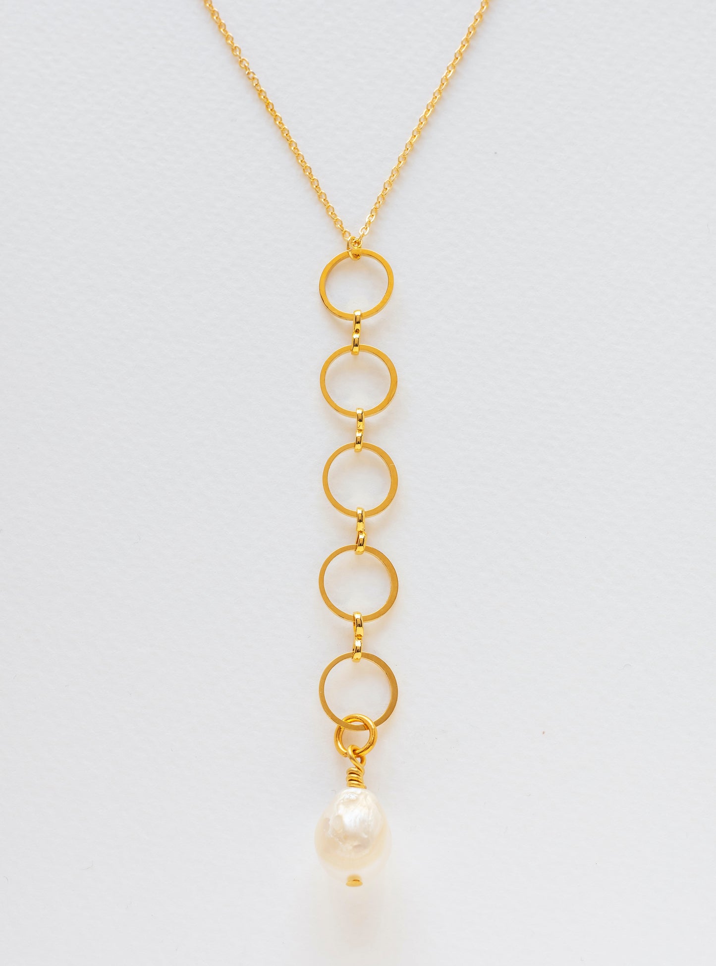 Long gold-plated necklace with circles interlinked and finished in a freshwater pearl.