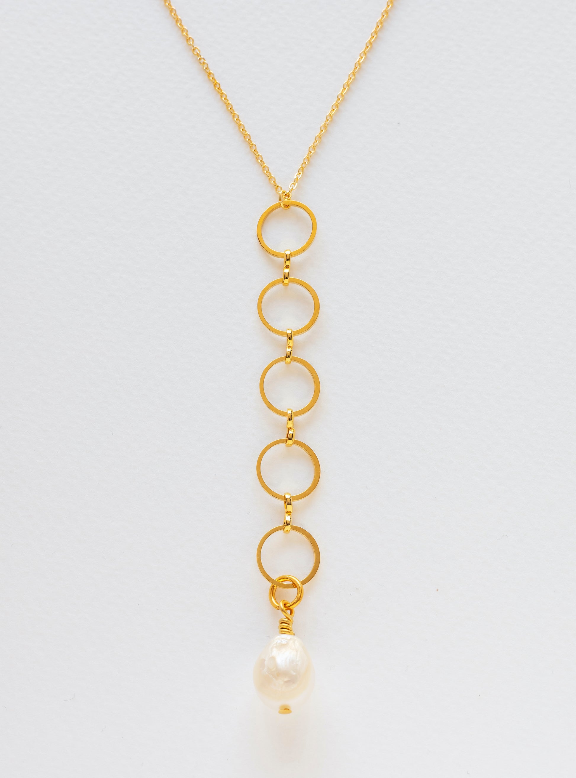 Long gold-plated necklace with circles interlinked and finished in a freshwater pearl.