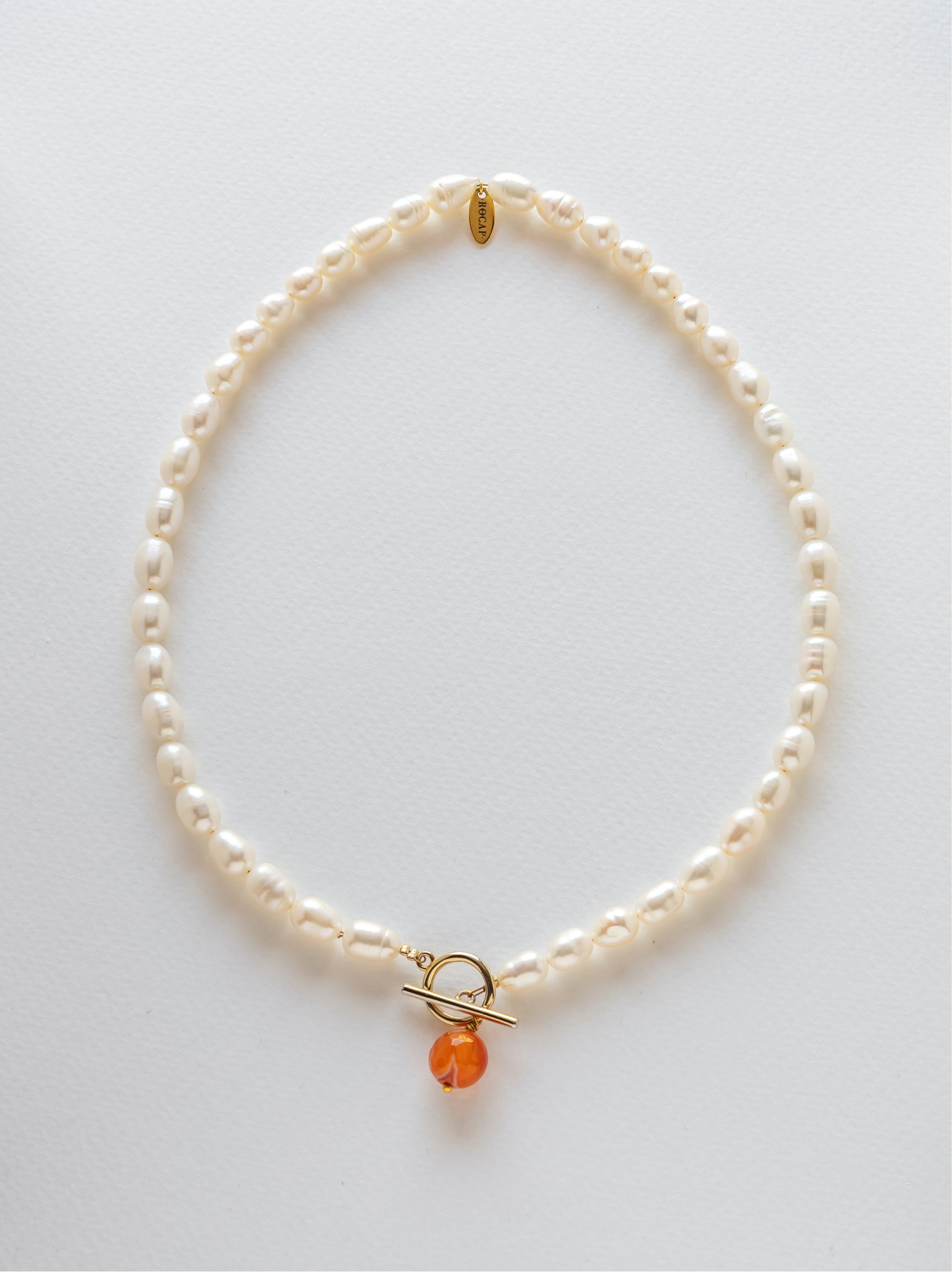 Pearl necklace with a clasp and a carnelian crystal pendant on the front.