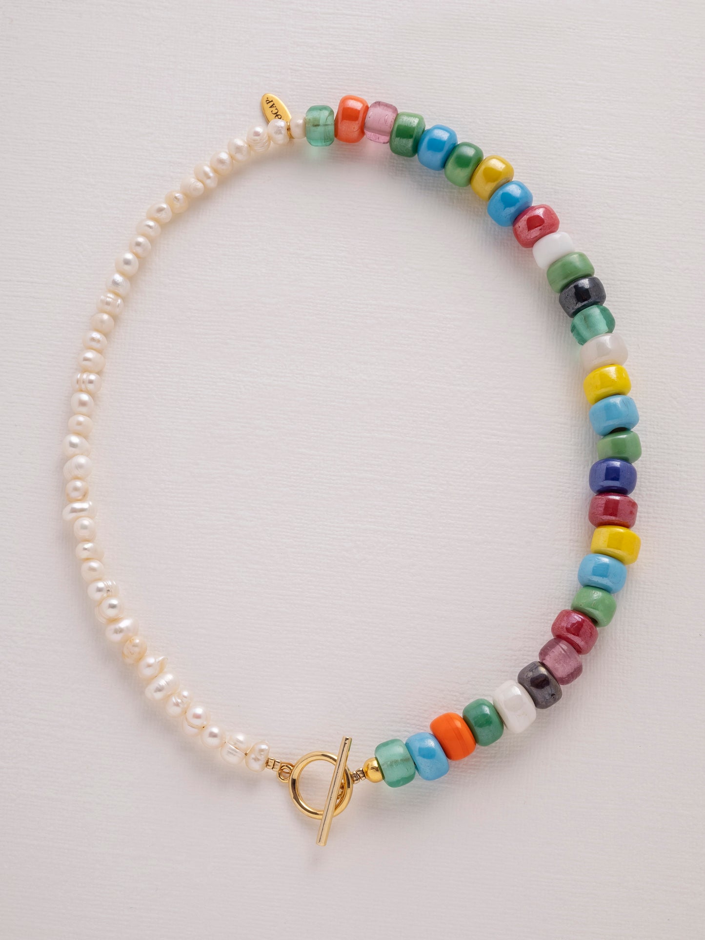 Asymmetric necklace made of recycled rainbow crystal crow beads and freshwater pearls with a gold-plated toggle clasp.